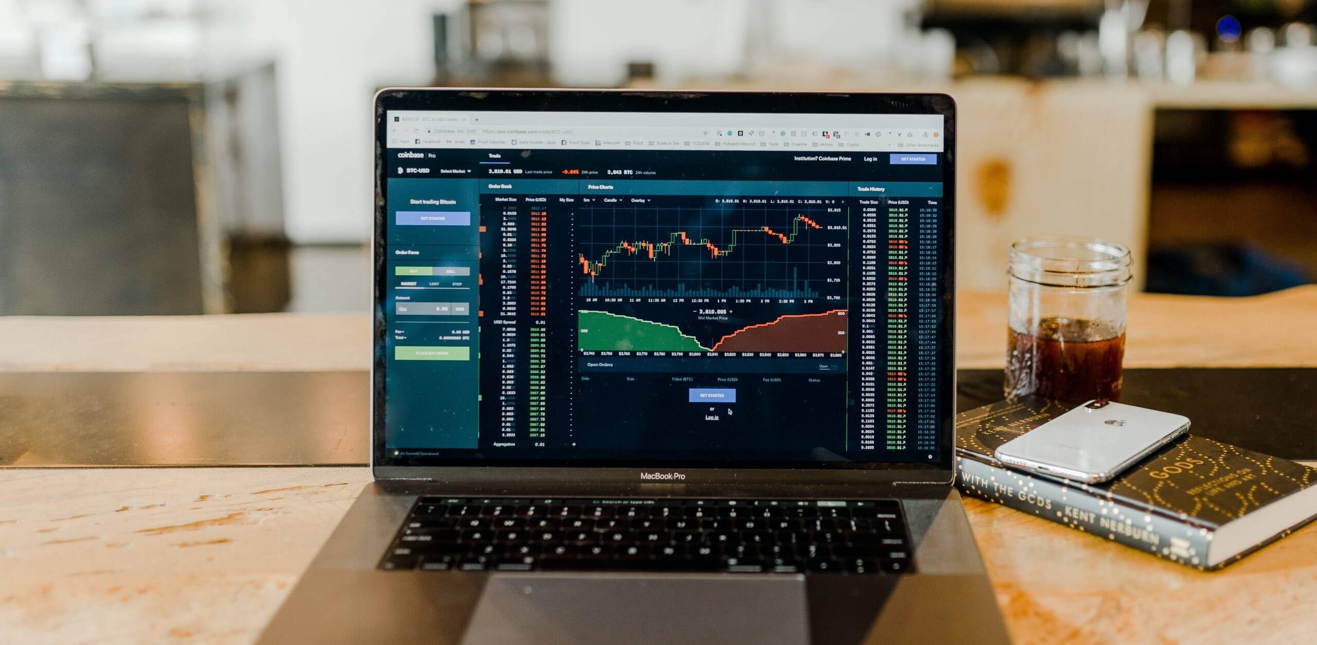 Desk with a laptop displaying a healthcare analytics dashboard, alongside a book, a cup of tea, and a mobile phone